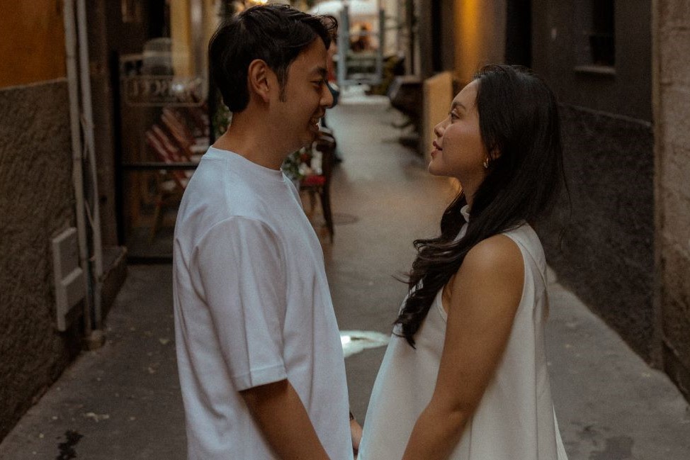 Couple habillé en blanc se regardant dans les yeux dans une ruelle